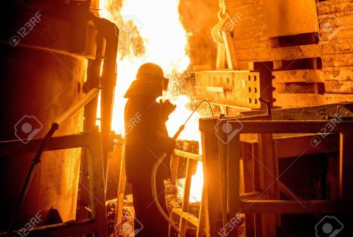 Steel worker in front of furnace fire in steel foundry